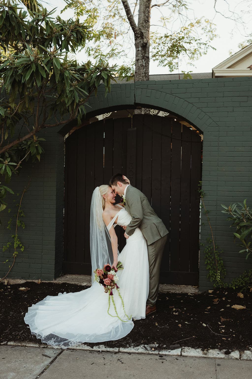 Ben and Elizabeth beneath a green brick arch at Justine’s Secret House in Austin